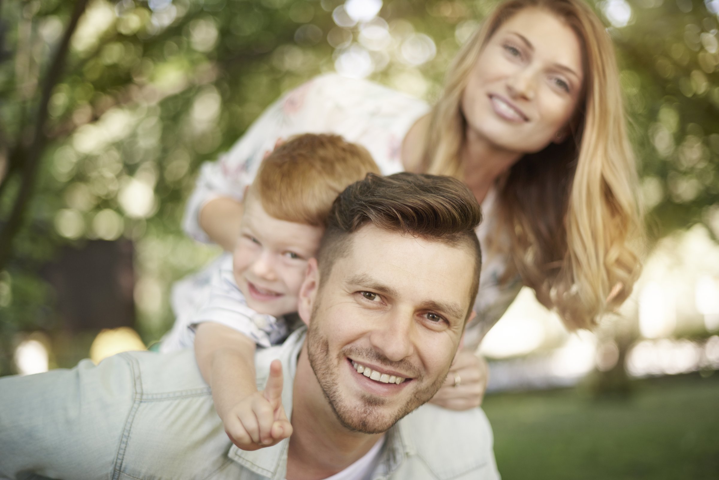 Uśmiechnięta rodzina – tata z synem na barana i mama